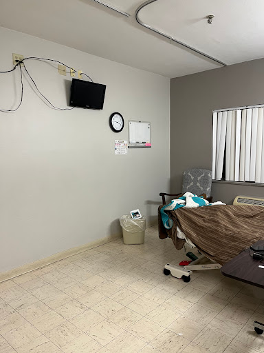 A view of a hospital room featuring a bed, a TV mounted on the wall, and a clock.