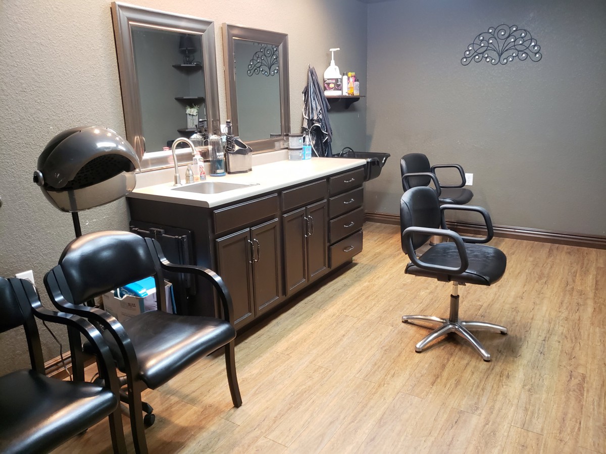 A neatly arranged salon with chairs, mirrors, and a hair drying station.