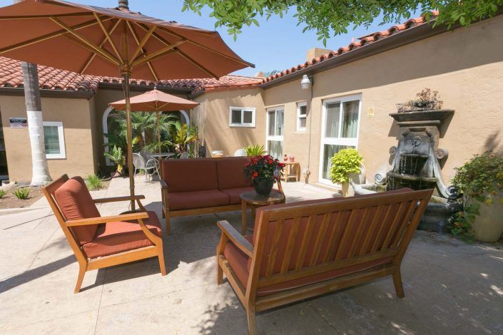 A sunny backyard patio with comfortable outdoor seating and umbrellas.