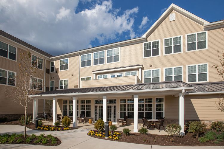 A modern residential building with a landscaped front and a clear sky in the background.