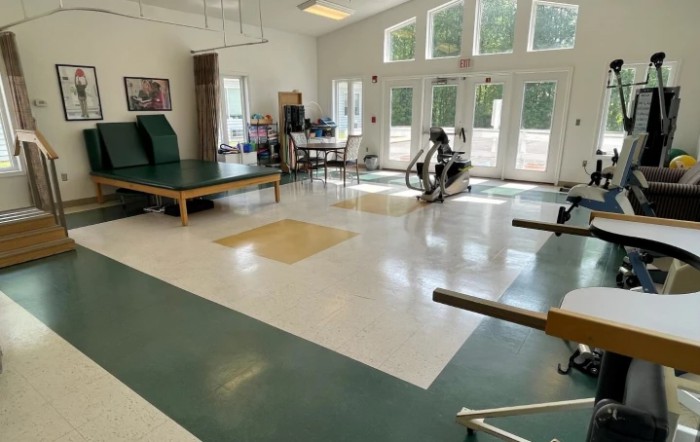 A spacious physical therapy room equipped with exercise machines and therapy tables.