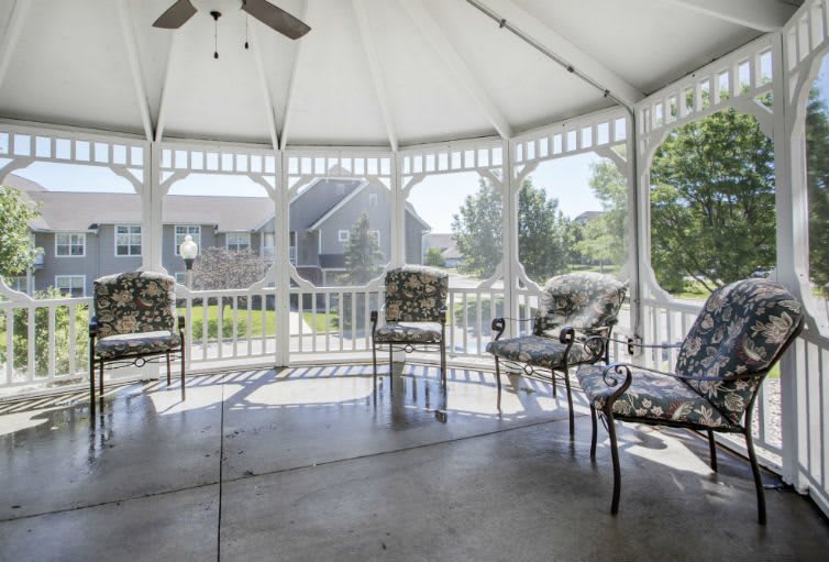 A gazebo with elegant patio furniture, providing a serene outdoor seating area on a sunny day.