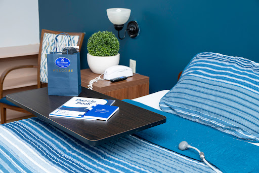 A cozy bedroom setup featuring a blue accent wall, striped bedding, and a neat nightstand with decorative touches.