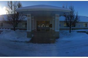 A building entrance surrounded by snow during the evening.