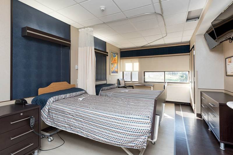 A hospital room with two beds and curtains.