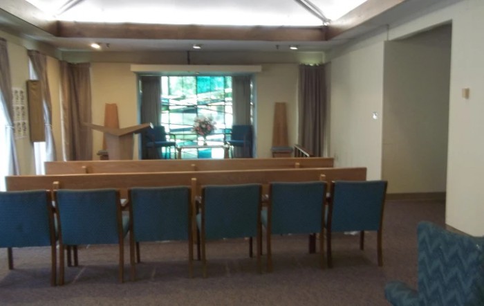 Interior of a church featuring pews, an altar, and stained glass windows.