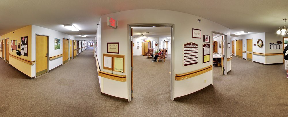 A carpeted hallway leading to a waiting area with seating visible through an open doorway.