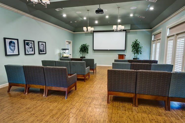 An empty conference room with arranged seating facing a projector screen.
