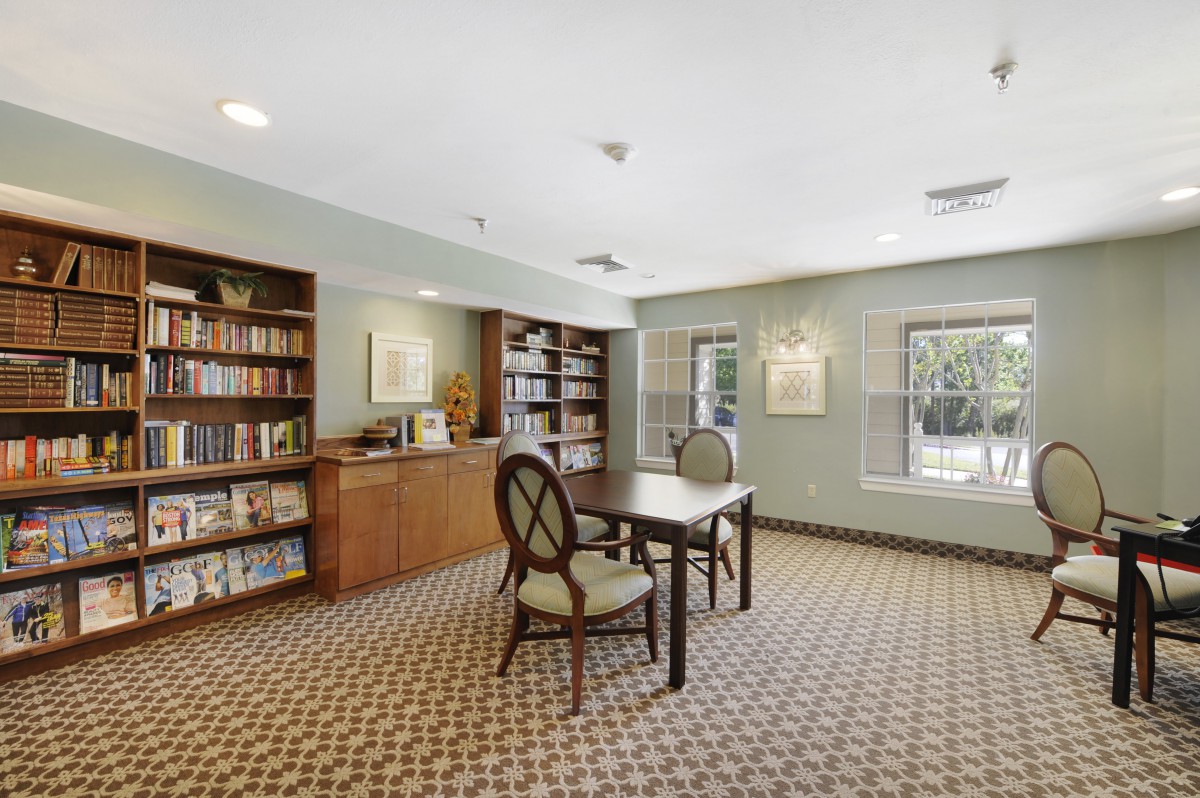 A cozy library interior with bookshelves, a reading table, and chairs.
