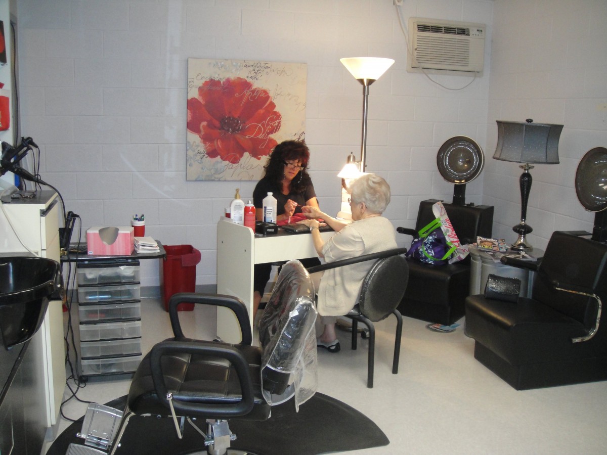 A beauty salon where a stylist is performing a manicure for a client.
