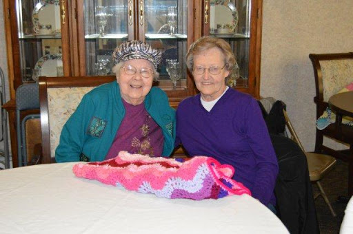 Two elderly women enjoying their time together while working on a knitting project.