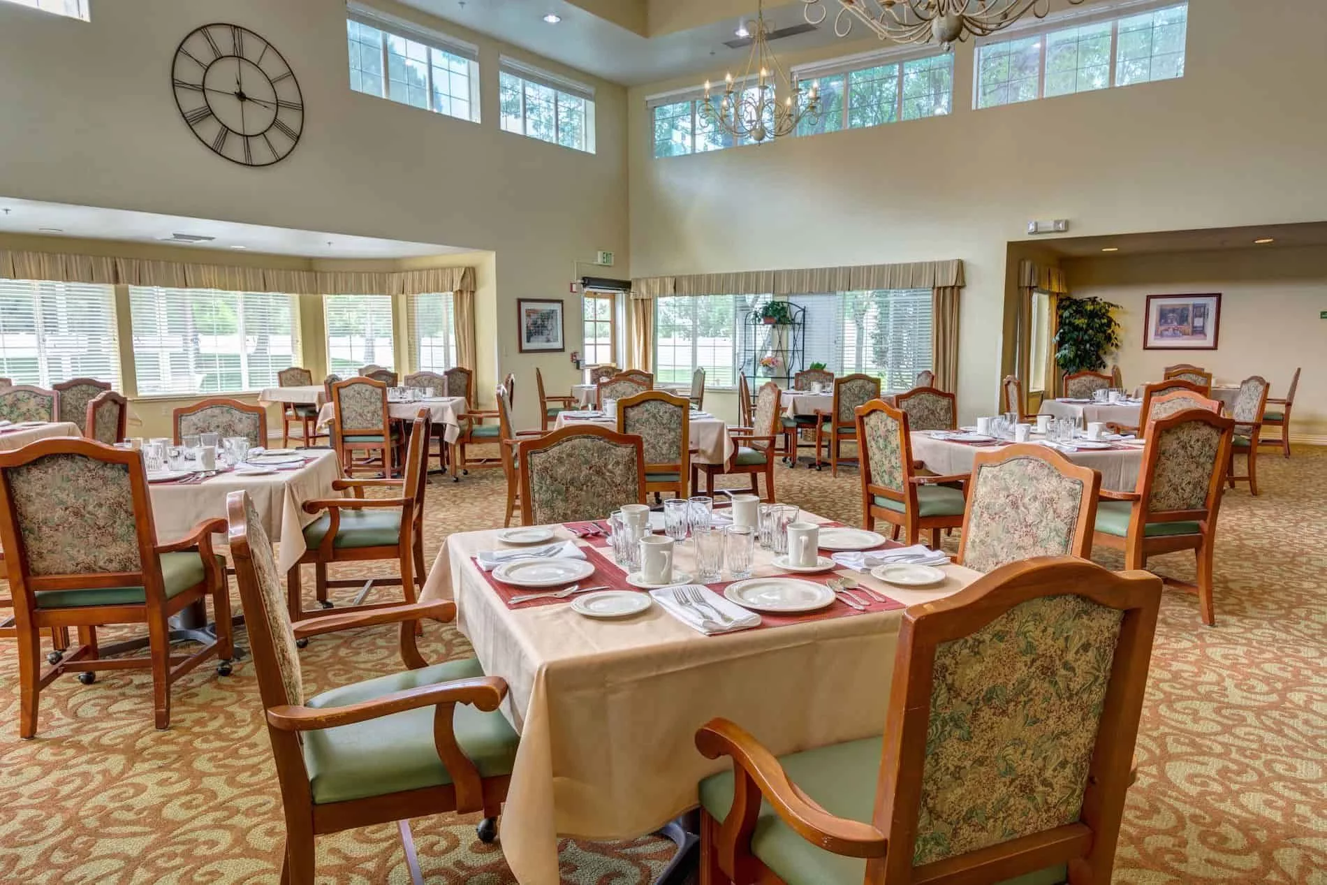 An elegant dining area with neatly arranged tables and chairs, featuring large windows that brighten the space.