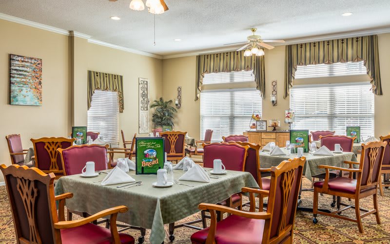 A well-set dining area with tables and chairs, featuring elegant decor and natural lighting.