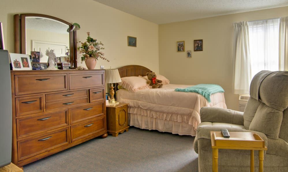 A cozy bedroom with a neatly made bed, dresser, and decorative items.