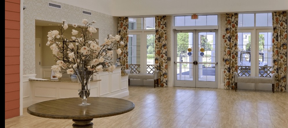 A bright and welcoming lobby with floral decor and large glass doors.