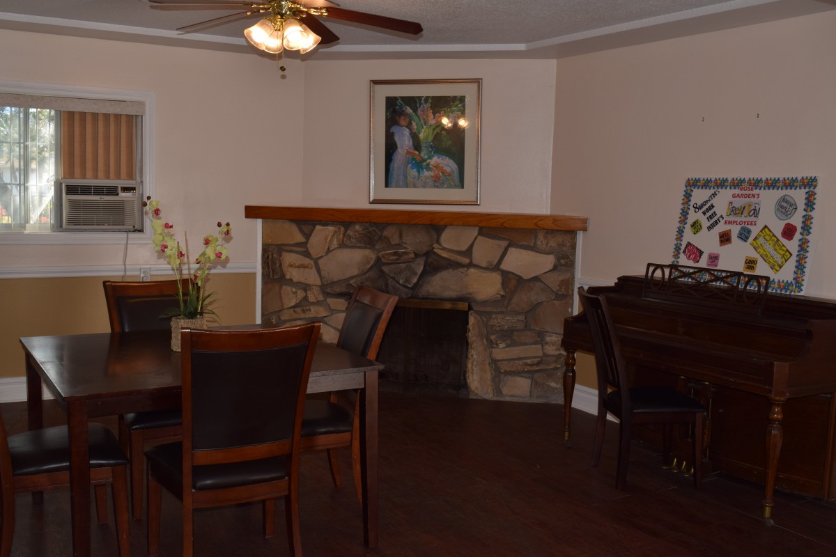 A cozy living room with a stone fireplace, dining table, and a piano.