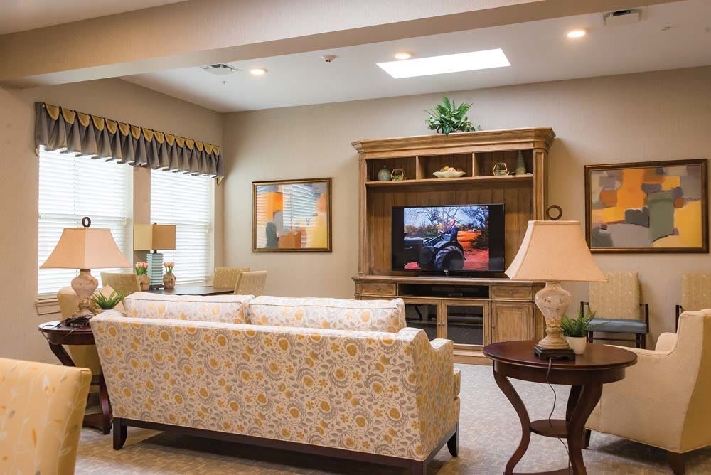 A cozy living room with a patterned sofa, wooden entertainment center, and television.