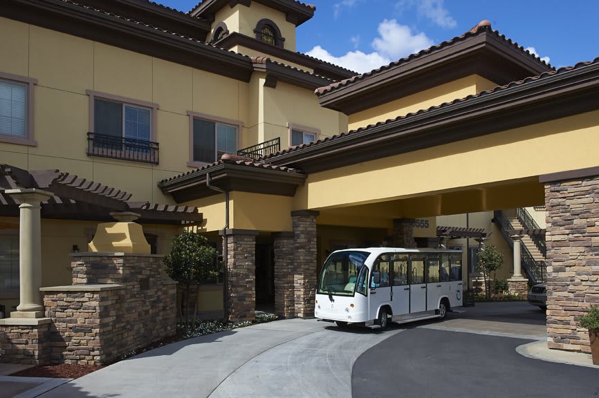 A small shuttle parked at the entrance of a large building with distinctive architecture.