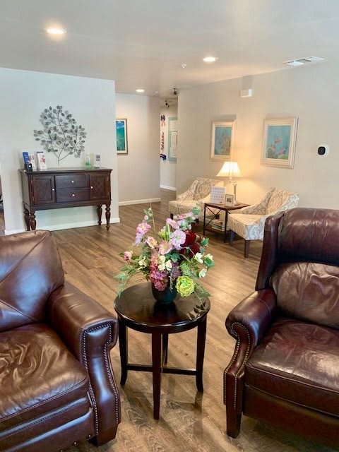 A cozy living room with leather chairs, a coffee table adorned with flowers, and artwork on the walls.