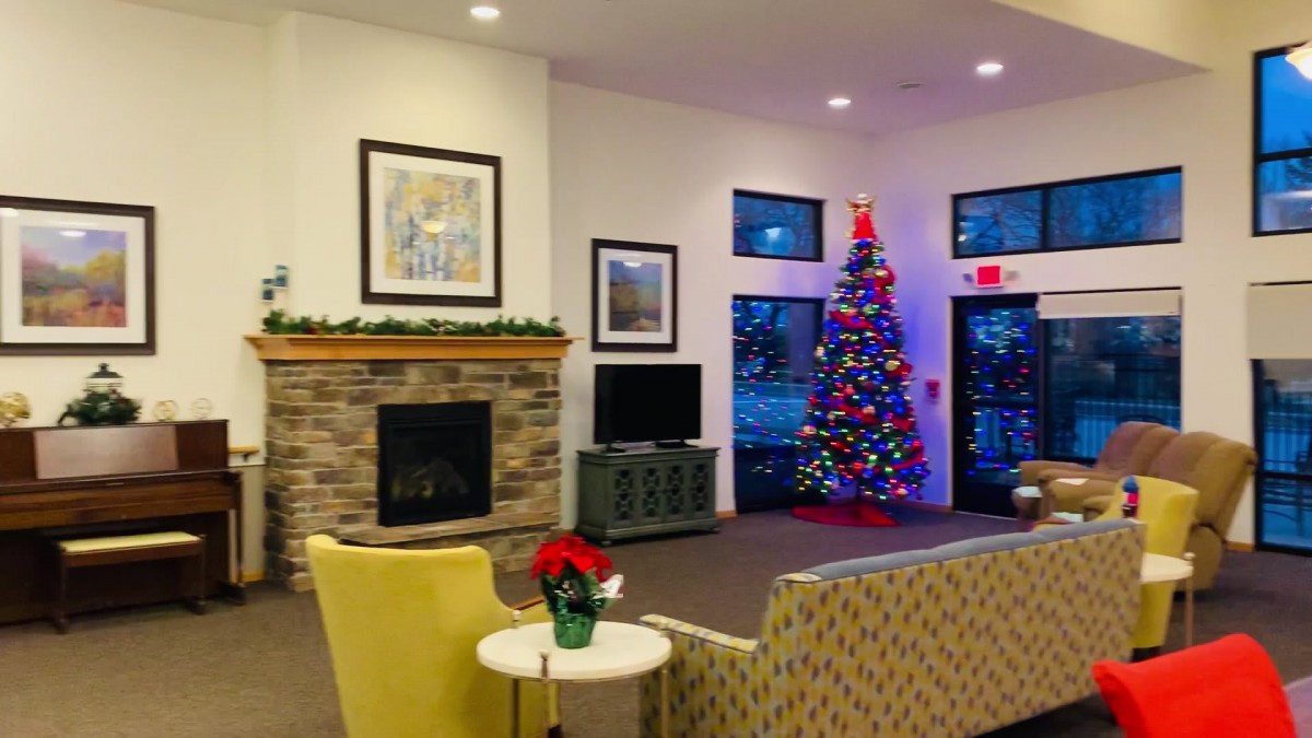A cozy living room with a decorated Christmas tree and a warm fireplace.