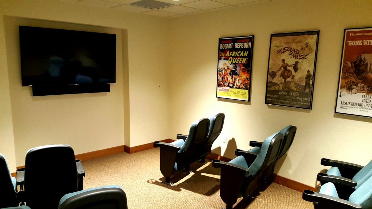 A cozy home theater room with comfortable seating and movie posters on the walls.