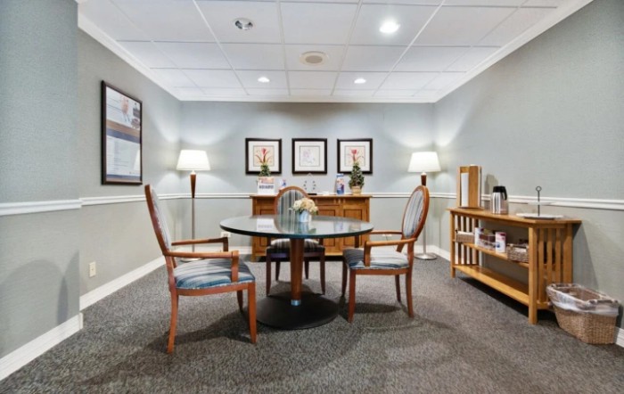 A small conference room with a round table and chairs, featuring elegant decor and framed artwork on the walls.