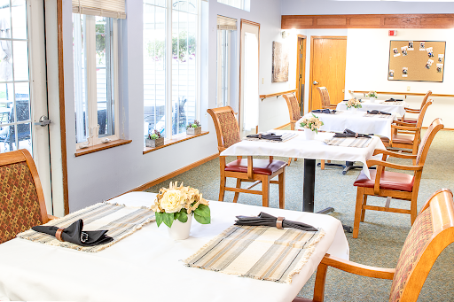 A beautifully arranged dining area, featuring tables set for guests with natural light streaming in.
