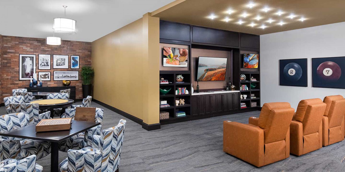 A modern lounge area featuring comfortable seating, built-in bookshelves, and a large television.