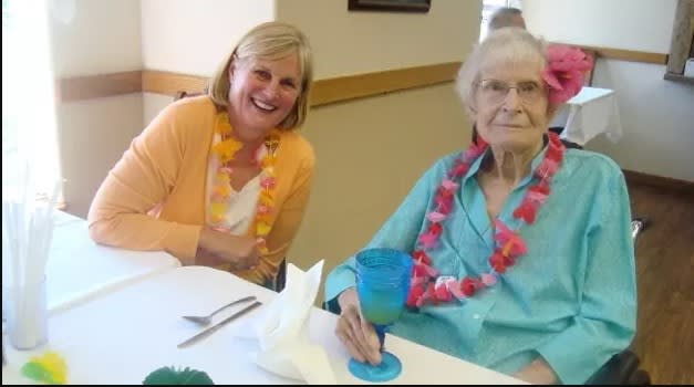 Two women enjoying a celebration, adorned with leis and smiling.