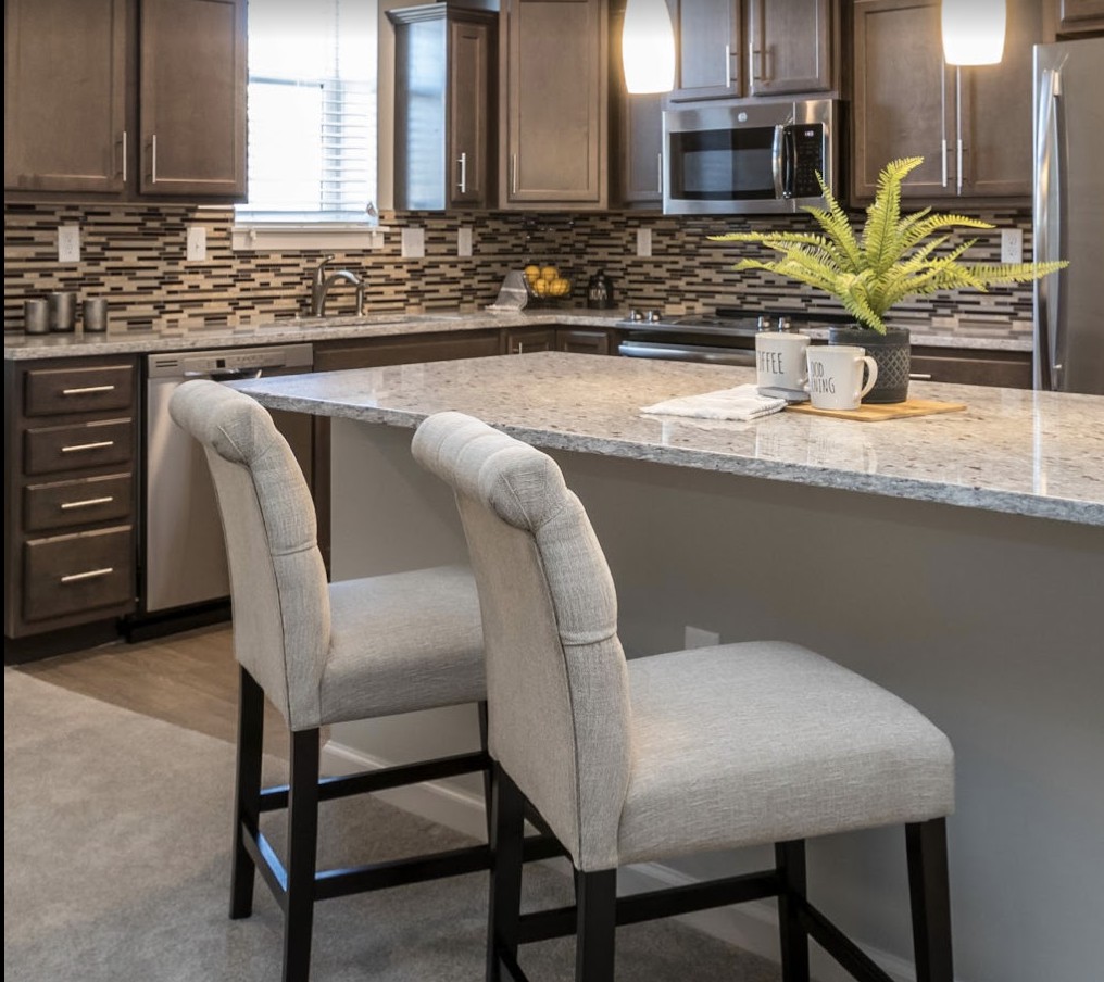 Modern kitchen with a central island and bar stools, featuring sleek cabinets and a stylish backsplash.