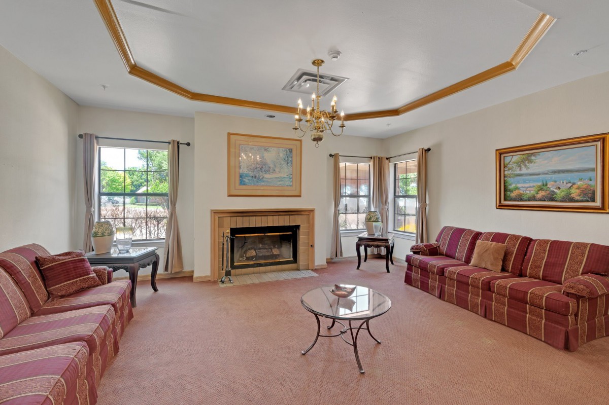 A cozy living room with sofas, a fireplace, and a chandelier.