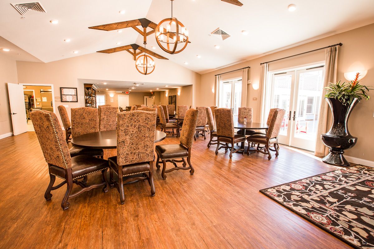 A spacious dining room with elegant furnishings, featuring wood flooring, round tables, and stylish lighting.
