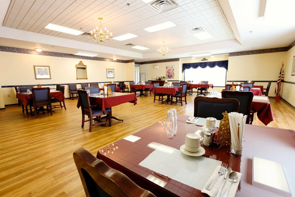 A well-lit dining room with neatly arranged tables and chairs on a wooden floor.