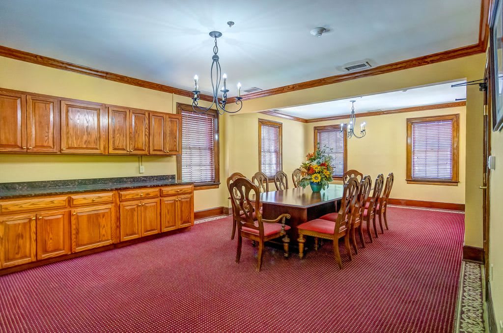 A spacious dining room with traditional wooden furniture and elegant chandeliers.