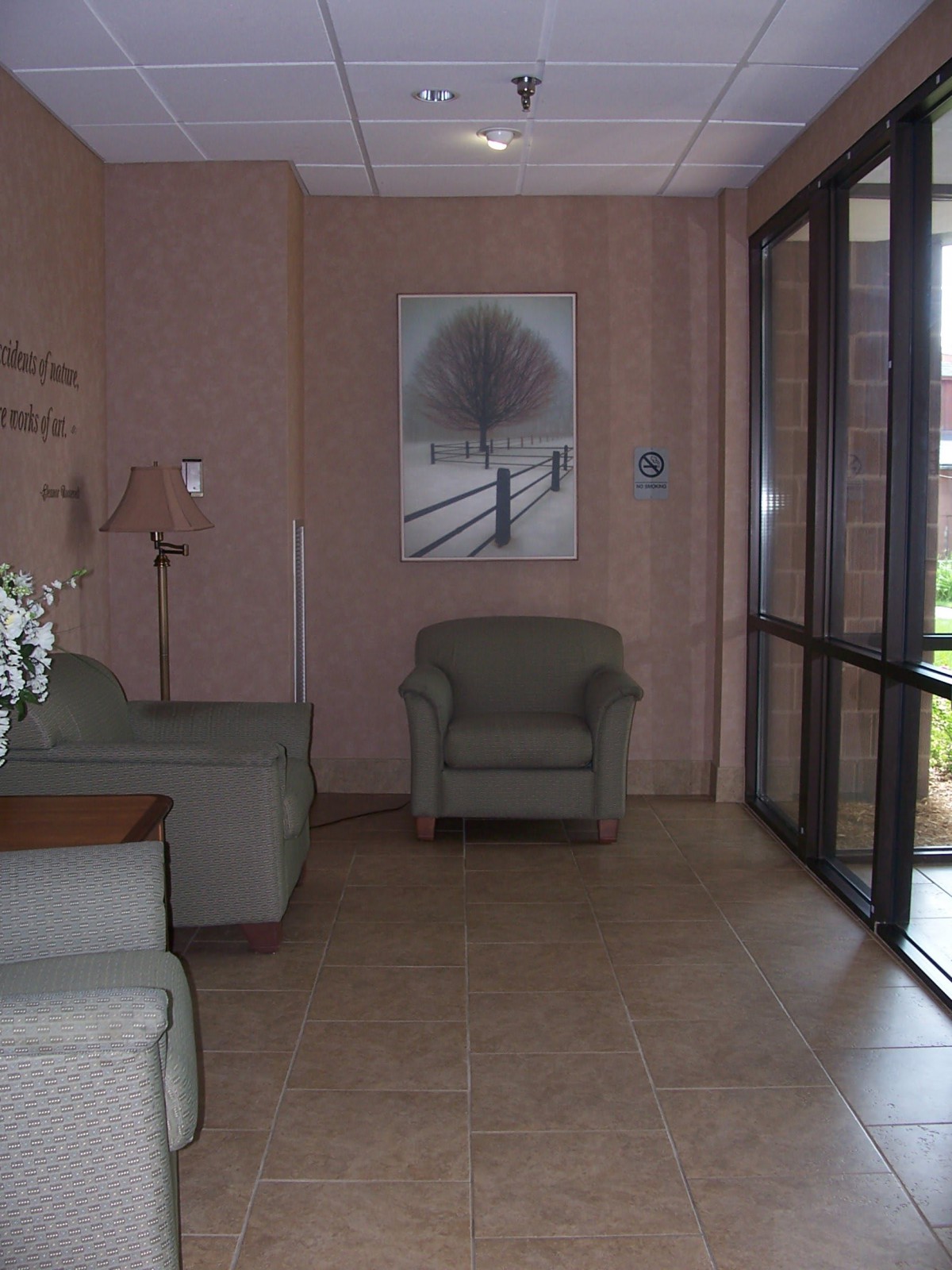 A cozy lobby area with armchairs, a sofa, a lamp, and a painting on the wall.