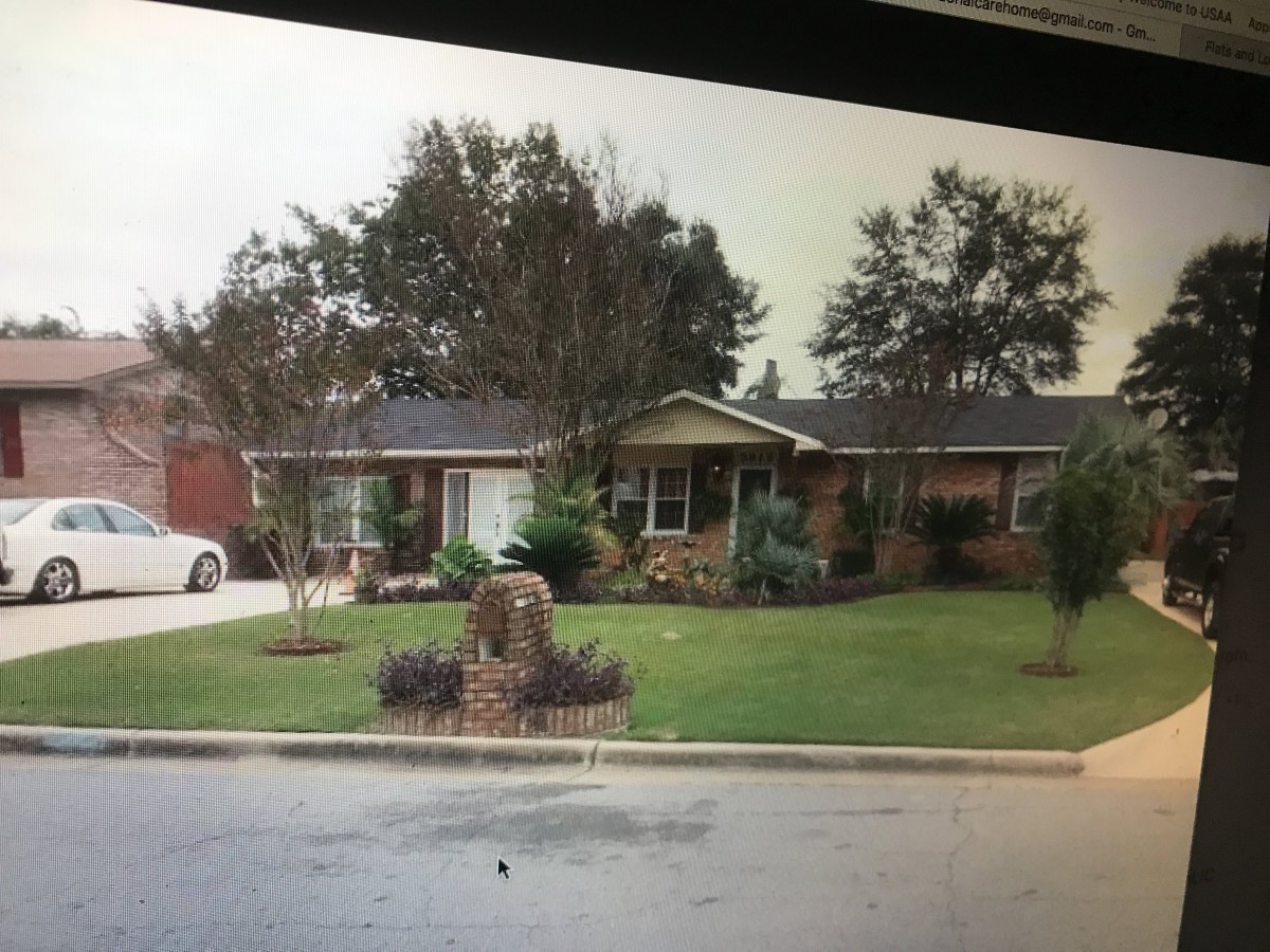 A suburban house with a well-maintained lawn and trees in the front yard.