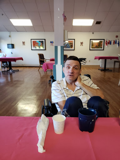 A person seated in a wheelchair at a dining table, set in a cozy indoor environment.