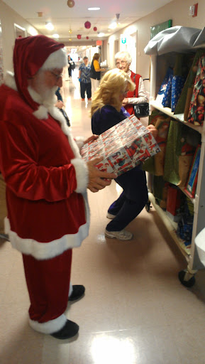 A festive scene with someone dressed as Santa Claus holding a gift while shopping for Christmas decorations.