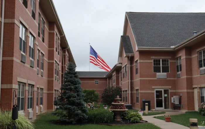 A view of a brick building with an American flag in the courtyard.