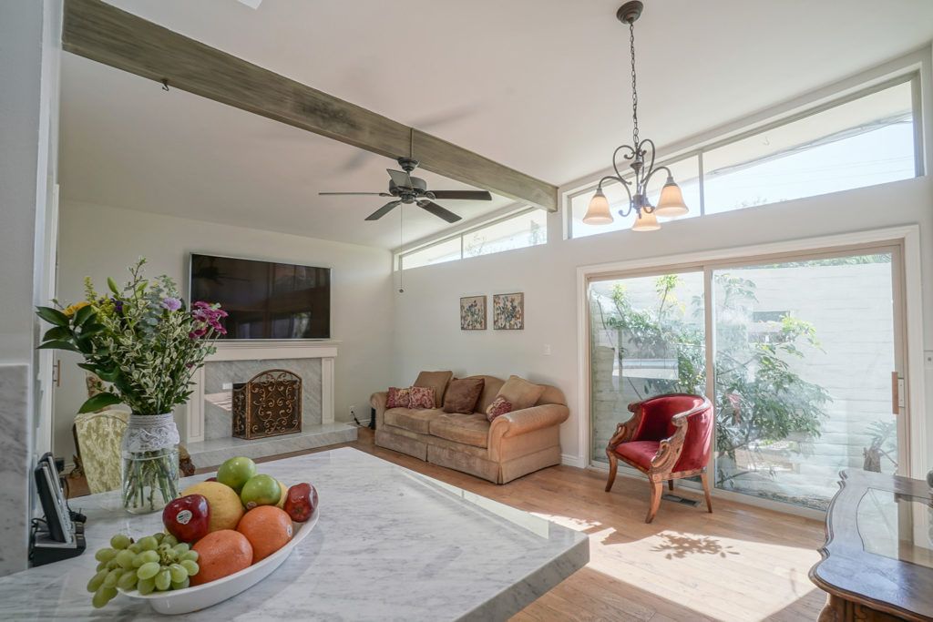 A modern living room with a comfortable sofa, fireplace, and a large TV. Natural light flows through the windows, illuminating the space.