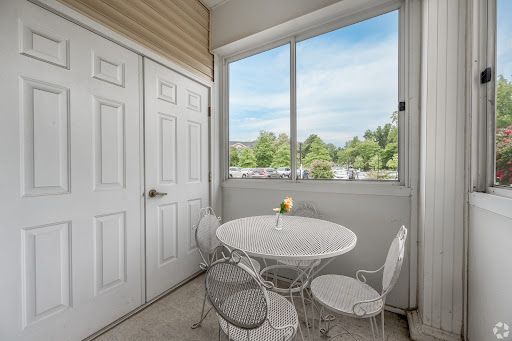 A cozy dining nook featuring a white table and chairs, illuminated by natural light from the large window.