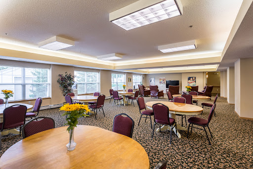 A spacious and well-lit dining area with tables and chairs, featuring a vibrant flower arrangement.