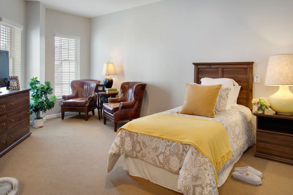 A cozy bedroom with a single bed and elegant armchairs by the window.
