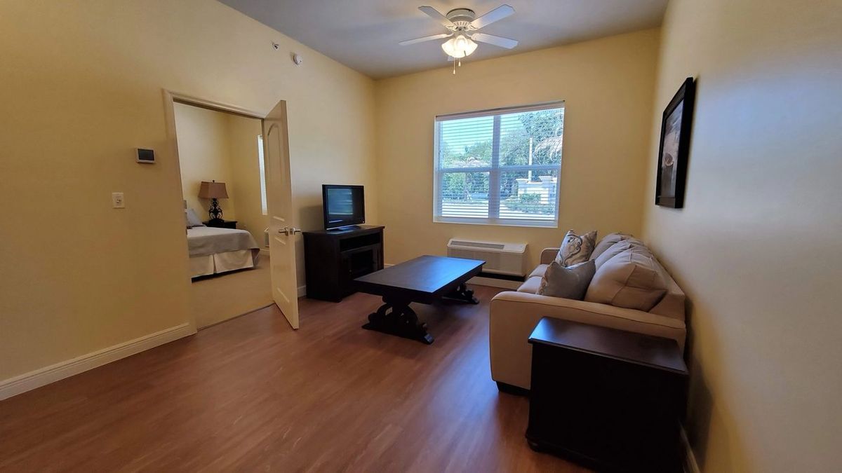 A cozy living room with a sofa, coffee table, and television near a window with natural light.