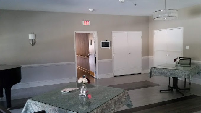 An interior view featuring a hallway with an exit sign, a table adorned with flowers, and carpeted flooring.