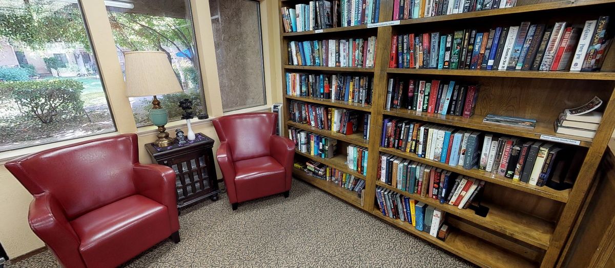 A cozy reading corner with red chairs and a bookshelf filled with books.