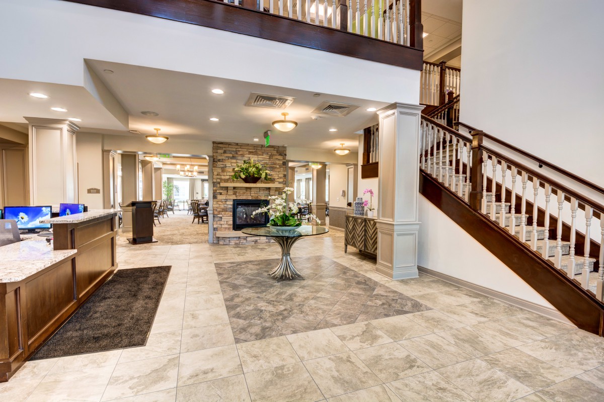 A spacious and elegantly decorated lobby with a central fireplace, staircase, and welcoming decor.