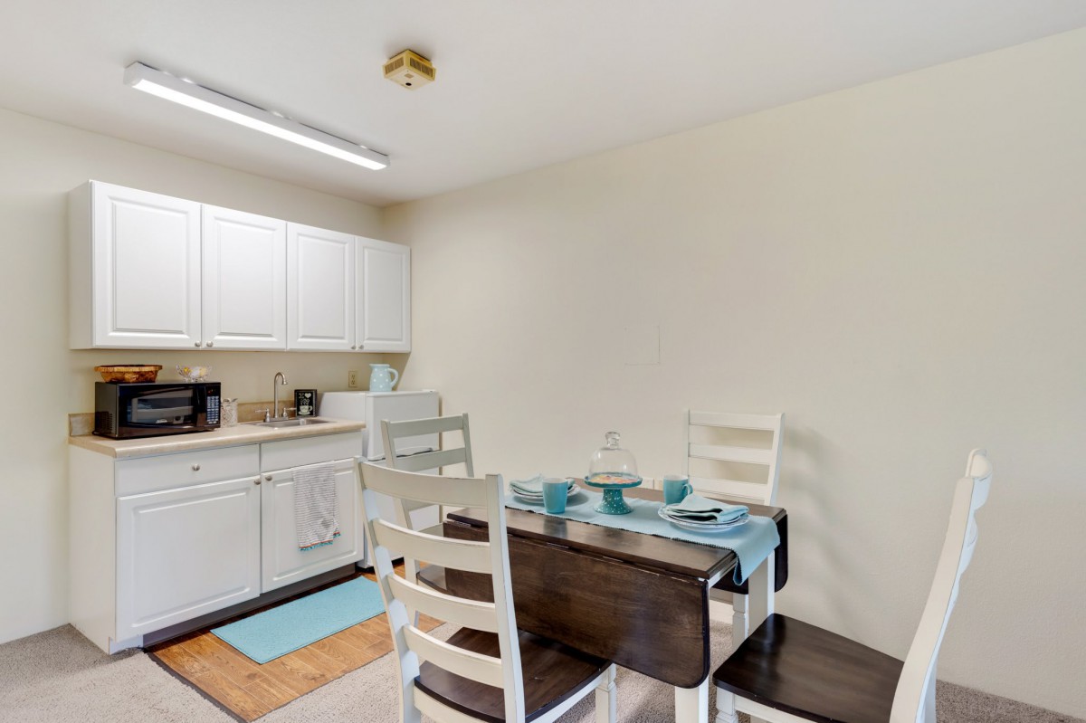 A modern kitchen and dining area with white cabinets and a neatly set dining table.