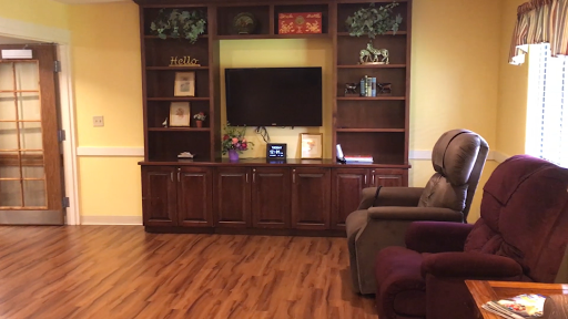 A cozy living room setup featuring a wooden TV cabinet with shelves, a television, and comfortable seating.