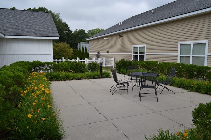 A peaceful patio with outdoor furniture surrounded by lush garden landscaping.